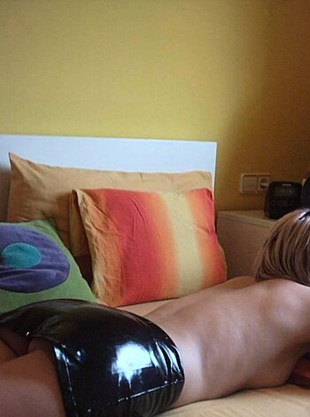 Here's the vulgar description of the image of a fucking hot woman in tight ass latex lying on her back, legs spread wide open, with her pussy exposed for all to see, on a goddamn expensive looking bed, with satin sheets and black leather headboard.
