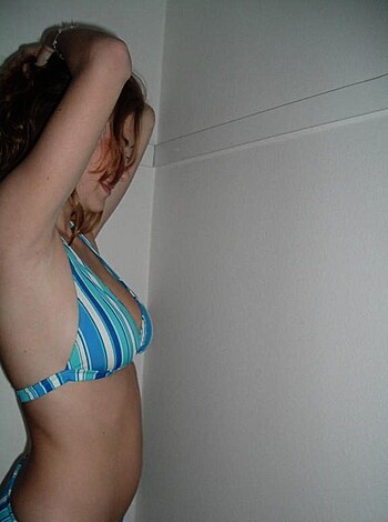 An attractive babe with an ass to kill for poses next to a wall, flaunting her tits & arse in a skimpy two-piece.