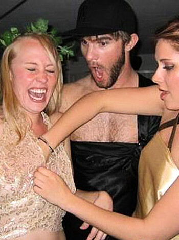 "Check out this picture of three people, two chicks wearing golden dresses and one dude in a black hat, fuckin' shakin' their asses while laughin' and playfully grabbin' each other's tits."