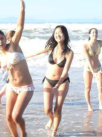 Four dumb sluts frolic in bikinis on the sandy shore, guffawing like retarded cunts while horsing around on the beach with childish glee.