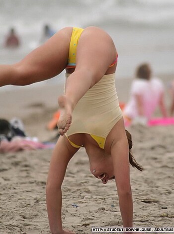 """
Here's a picture of a chick flipping upside down while wearing nothing but her ass-less bikini bottoms, on some damn beach surrounded by sandy dunes and blue sky. She looks like she's having fun, but if you ask me, it just makes my dick hard as fuck to see a fine pussy like that with no top.
"""