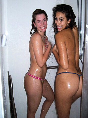 The image depicts two horny chicks showering together, with their pussies exposed and faces grinning.