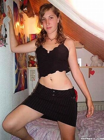 A young chick in a tight black bra and mini-skirt, showing off her hot bod with an innocent smile.