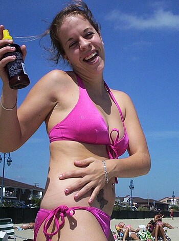 "Here's a chubby blonde woman in pink nipple tassels, with a face full of joy, holding a Heinz bottle on the sandy shore."