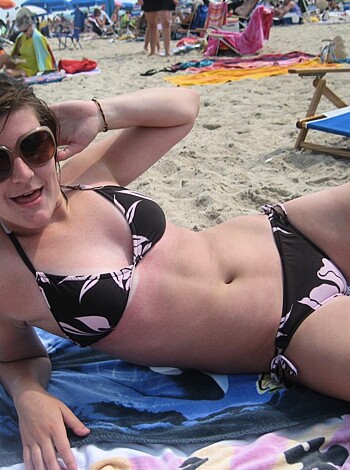A bitch in a two-piece sunbathing by the shore, her tits barely covered up, and her ass hanging out.