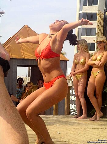 Vulgar description: This image features a scantily clad hoochie in a skimpy red two-piece who's shaking her ass like a fucking stripper.