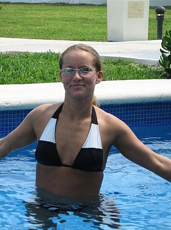 A bare ass chick soaking her tits in a swimming pool.