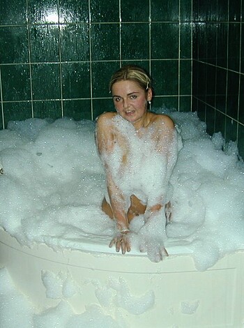 A scantily clad chick soaks her tits in a bubble bath, on display for all to see.