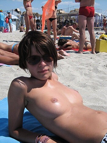 A nude chick sunbathing with her tits out on a flimsy piece of fabric while she tries to look sexy for some dude taking pics.