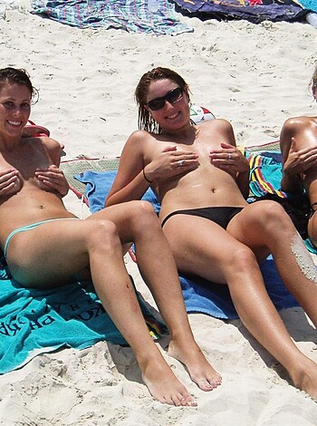 Three bare-assed babes sprawled out on beach towels, grinnin' like fools at the lens.