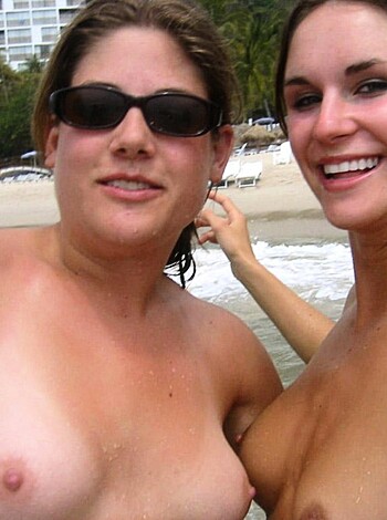"A bunch of topless chicks sunbathing on the sandy shore, with one babe sporting a pink flowery headband."