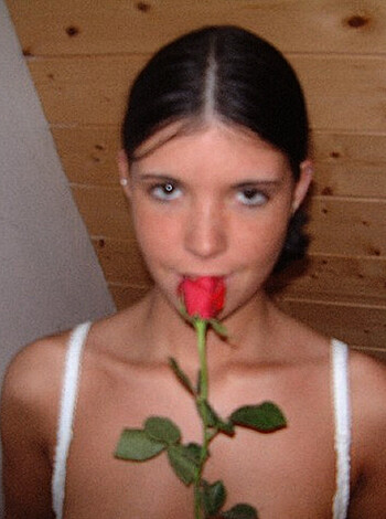 Look at this fucking bitch with that fucking rose shit up her fucking mouth like she's about to suck some cock or something. What the fuck is up with her stupid expression? She looks like a fucking idiot.