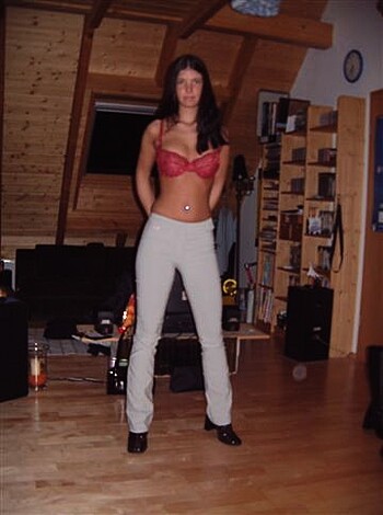 The chick in the red bra and denim shorts is bent over, showing off her ass in some generic fuck pad.