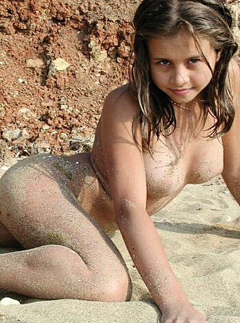 A naked kid ass-facing the camera, sprawled on hot sand, staring right into your soul with those innocent eyes, and her pussy looks like a plump peach waiting to be eaten.