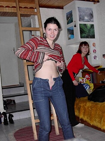 "This image shows a busty broad with her sweater unbuttoned, and some other skanky cunt pointing at her tits."