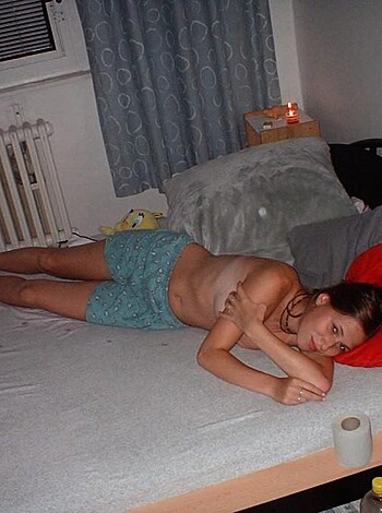 This image depicts two topless chicks snuggling up in a bed with their tits out, ready for some action.
