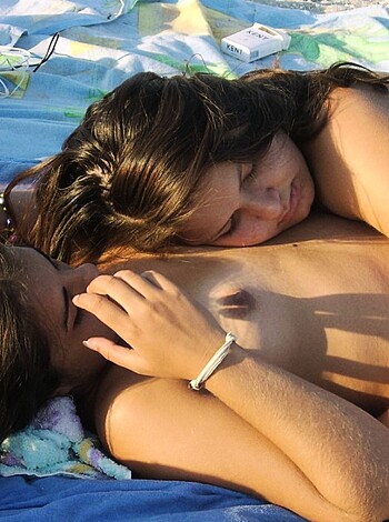 A vulgar description of this image would be something like "Two fucking hot chicks lying naked on top of each other, with their pussies rubbing together."
