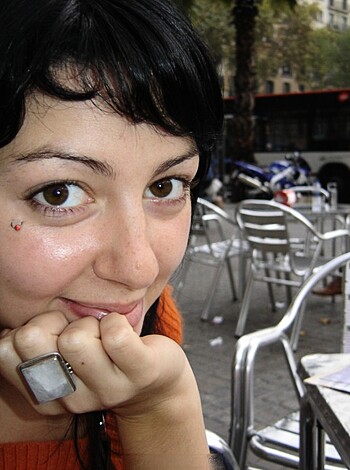 This chick is fucking smiling while she sits at a table at a cafe, looking directly into the camera.