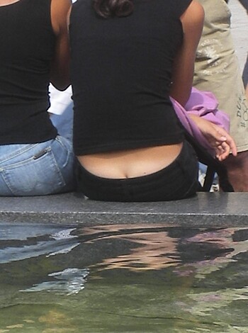 This image depicts a vulgar scene of a fat chick with ass acne and scars, taking a piss on a park bench while exposing her hairy crack and cellulite dimples.