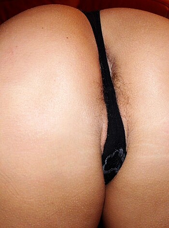 A babe's ass, with no face, wears black panties, as she stands on her tush.