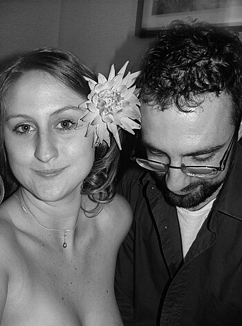 Fucking sexy chick with dildo up her ass and a fuckin' rose between those tits, while some nerdy asshole is lookin' at his goddamn glasses in the background like he has no clue what he's missin' out on.