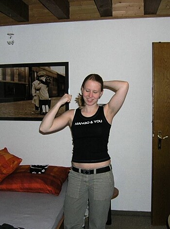 A hot chick showing off her meathead bicep pumps while posing in the boudoir.