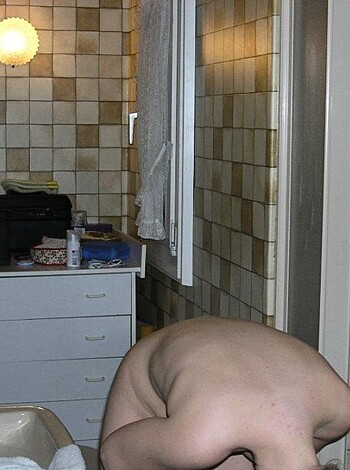 A naked ass-hole is crouched over a toilet seat.