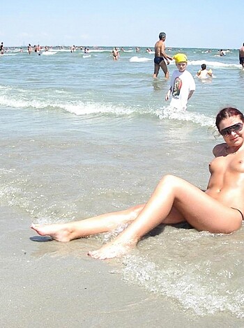 Here's an image of some hot chick with her tits hanging out on the sand, getting a tan.