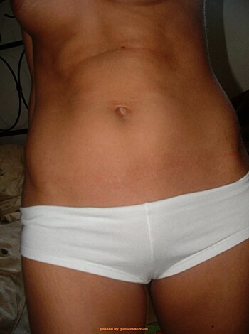 A bitch in her tight ass panties, showing off her shiny naked crack while she poses with a coy smile.
