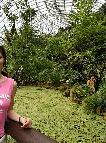 Here's the vulgar description of that image:
The chick with the rosy titties is posing in the greenhouse, fuckin' up all those plants and trees like some kinda garden gnome with her dumb bitch face and pink shirt.
