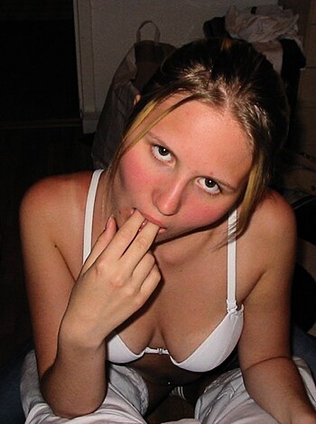 A young lady is pleasuring herself by licking her juicy fingers, while being completely nude.