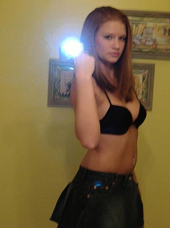 A hot chick in a tight bra and short skirt, snapping pics of her ass on her phone.