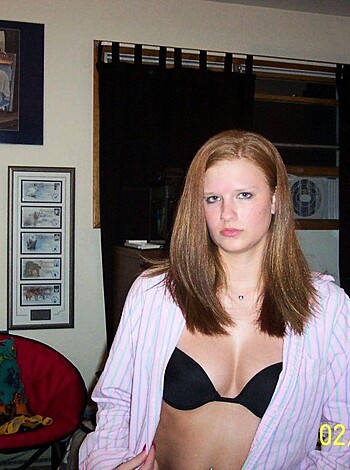 A fuckin' shitty photo of some bitch strippin' down to her panties and bra, sittin' on a fuckin' couch in some house.