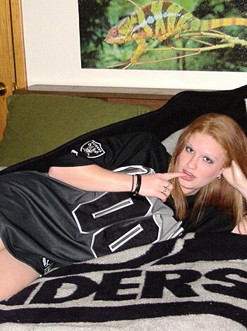 A scantily clad chick taking a nap on her bed with just a team jersey and some kind of sheet covering her ass.
