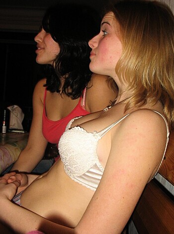 Two hoes hugging up on a sofa, both with their tits out.