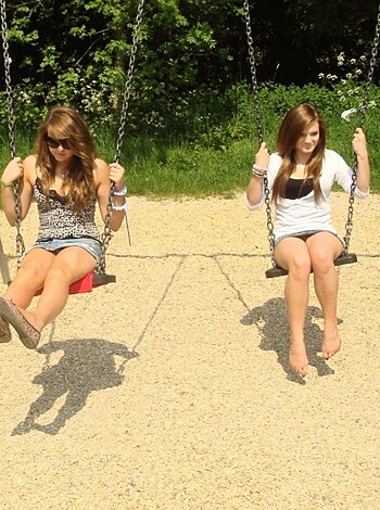 Two women on swings, pumping their sticks like they just don't give a f*ck.