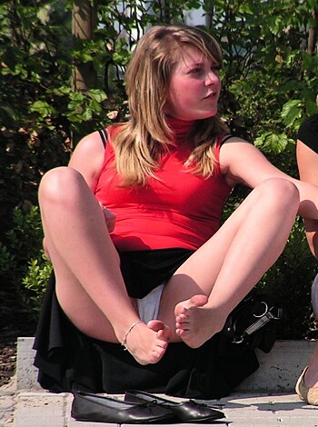 A hot chick in a short red dress with no shoes on her feet.