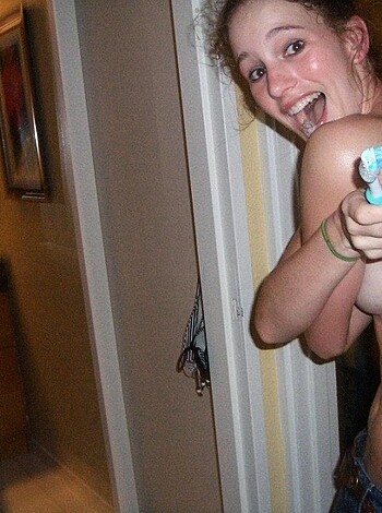 This image depicts a nude female who's apparently got her hands on a blue toothbrush, brandishing it towards the lens of the camera with an air of arrogance.