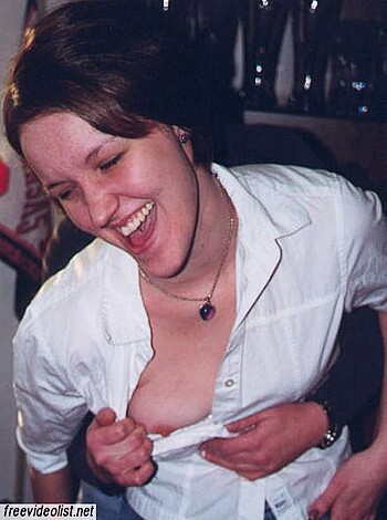 A busty chick playfully fondling her tits while grinning ear to ear.
