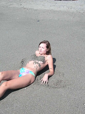 """
Hot chick on beach with tiny bikini, lying down naked, her pussy exposed.
"""