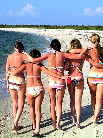 Four hot chicks stroll naked along the shoreline, bikini bottoms in hand.
