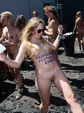 A group of naked individuals, mostly covered by colorful body paint, gathering outside with a bunch of random clothes hanging off their bodies like fucking retards.