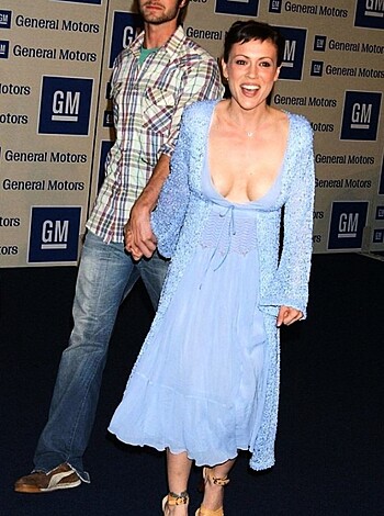 Fucking hot babe in a low cut dress struts her fuckin' tits down the red carpet with some dude in a checkered shirt, lookin' like they both got a goddamn hard-on for the cameras.