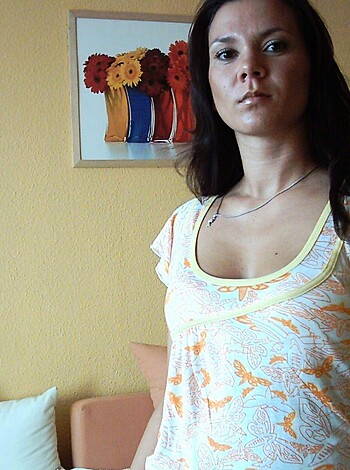 This image is of a woman who looks like she just fucked an orangutan, with her tits hanging out for everyone to see, wearing some kinda shitty day-glo shirt with a stupid yellow collar that makes it look like she's got a goddamn sunflower on her neck.

 (34 words)
