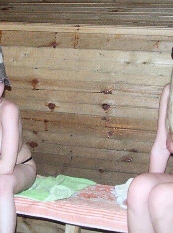 Two smoking hot chicks bare as hell, taking selfies together while sitting ass-to-ass on a wood bench, their tits jiggling with every move they make.