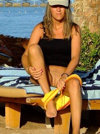 A slender chick reclines on a fucking beach chair, exposin' her tanned pins and thighs in a teeny bikini top, with no shoes 'n shit.