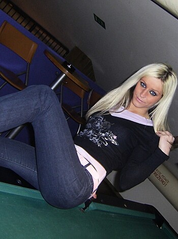 A chick perched on a billiards table, spreadin' 'er legs like she owns the joint.