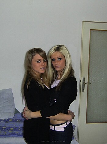 A pair of busty blonde bimbos striking a bodacious pose, fucking each other in their frilly panties while laying on their matching bed sheets.