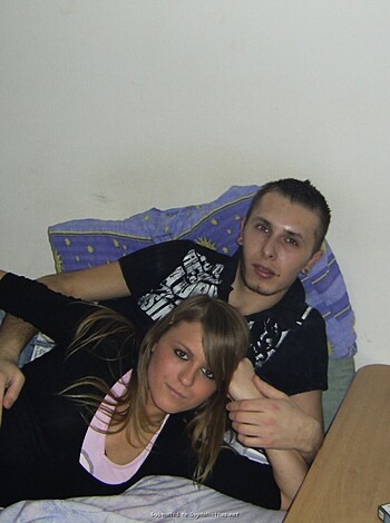 "A fucking happy couple kissing while holding hands with their arms around each other, posing for a photo."