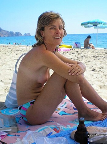 A topless bitch on the sandy shore, with her tits out and her nipples hard as rocks, sunbathing without a care in the world.